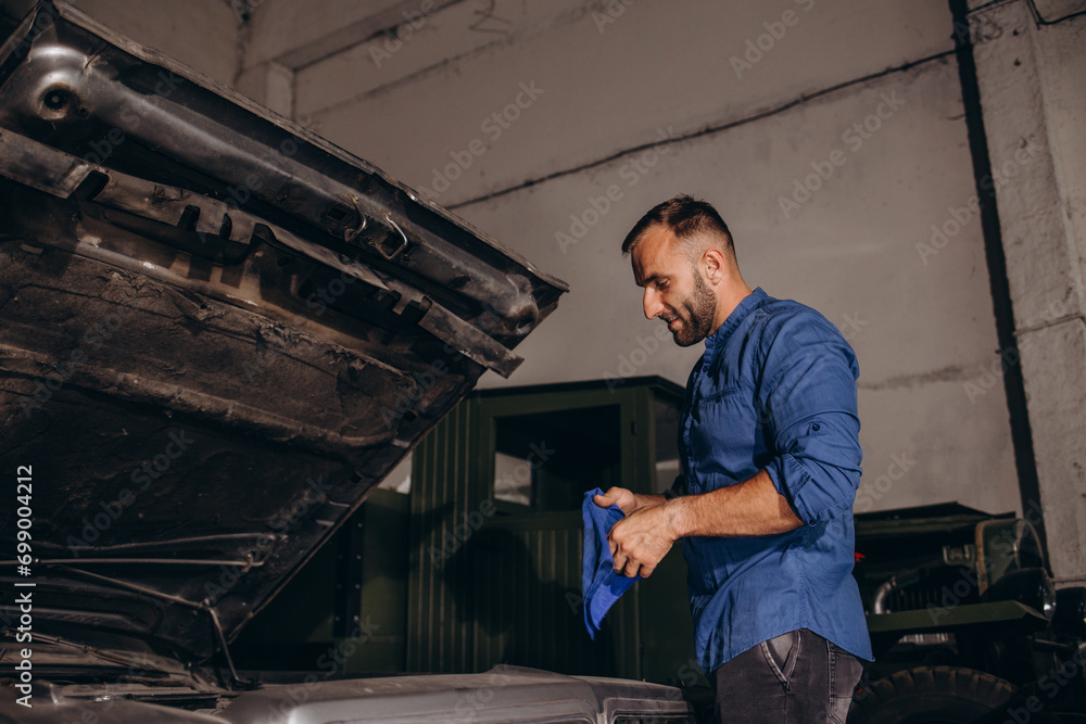 A man repairs an engine in a retro car A man repairs an engine in a retro car