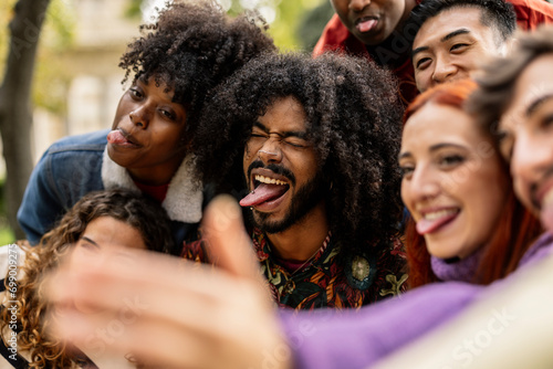 detail close up on young adult African American man with tongue gesturing joking with his group of friends while taking a selfie photo