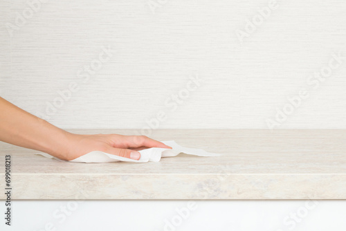 Bild auf Leinwand Young adult woman hand holding dry white paper napkin and wiping beige stone tabletop at home kitchen