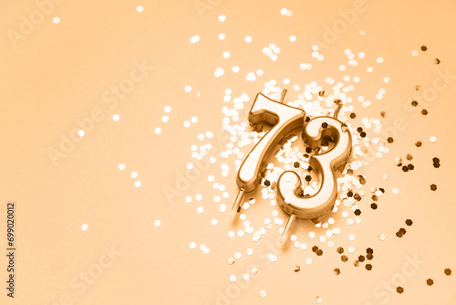 73 years celebration festive background made with golden candles in the form of number Seventy-three lying on sparkles. Universal holiday banner with copy space. photo