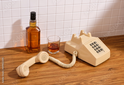 Whiskey bottle and vintage beige phone. Luxury composition.