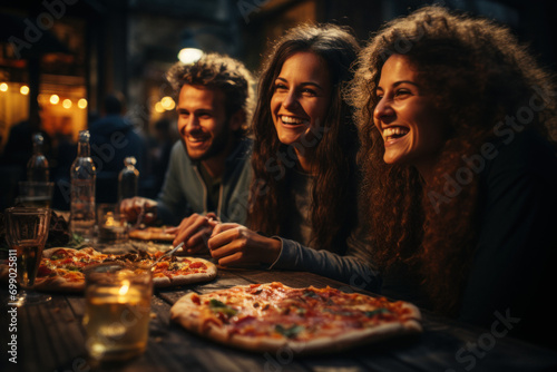 Happy young friends eating pizza in a restaurant photo