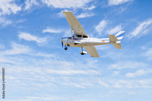 Single engine ultralight plane flying in the blue sky with white clouds