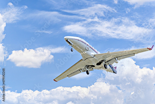 Private business plane flying under a blue sky with white clouds