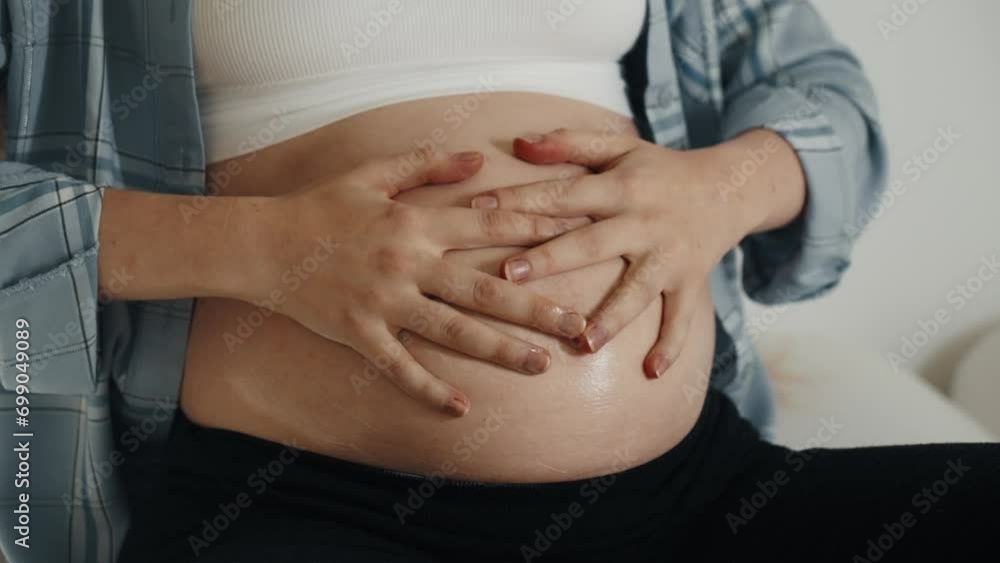 Woman massaging pregnant tummy by hands. Female doing massage with oil on belly during pregnancy to avoid appearance of stretch marks on skin. Expecting baby, healthy self cafe, bodycare concept. Woman massaging pregnant tummy by hands. Female doing massage with oil on belly during pregnancy to avoid appearance of stretch marks on skin. Expecting baby, healthy self cafe, bodycare concept.