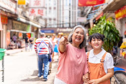 Happy Asian family grandmother and grandchild girl walking and shopping together at street market. Senior woman and little girl enjoy and fun outdoor lifestyle travel in the city on summer vacation.