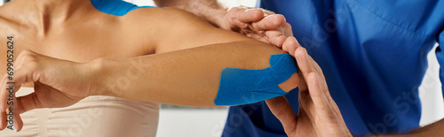 cropped view of doctor putting kinesiological tapes on elbow of young woman, healthcare, banner photo