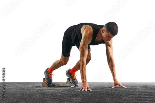 Young athletic man, professional jogger preparing to run while standing at low start against white pristine background. Concept of sport, active lifestyle, action. Copy space for text. Ad