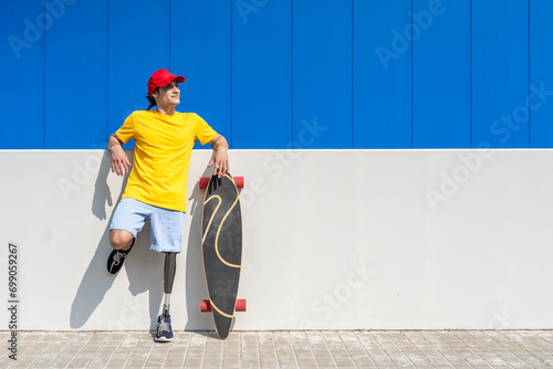 Smiling young man with disability standing near skateboard on sunny day photo