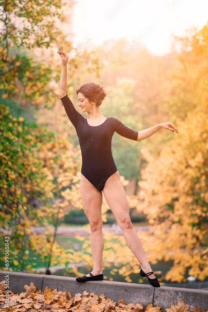 Beautiful female, ballerina, athlete in black bodysuit training in the park Beautiful female, ballerina, athlete in black bodysuit training in the park