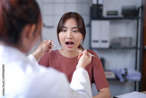 Asian dentist doctor women using explorer mirror tool to examining teeth of patient and explaining about oral dental treatments while discussion about dental health and healthcare in dental clinic