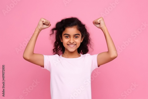 indian girl standing on pink background and showing arms muscles