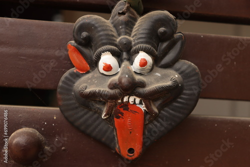 An Indian Black evil eye nazar battu mask with nimbu mirchi or lemon and chilly sign attached by string on iron gate, closeup