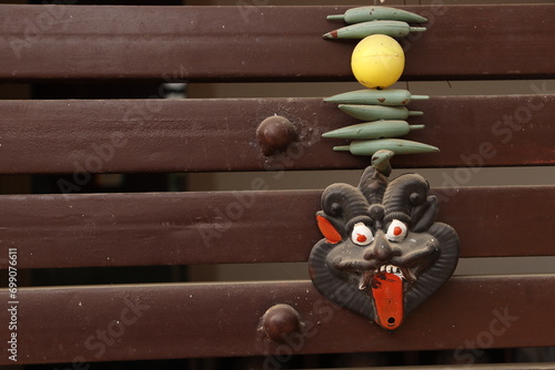 An Indian Black evil eye nazar battu mask with nimbu mirchi or lemon and chilly sign attached by string on iron gate, landscape