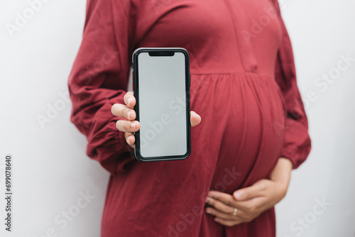 Muslim pregnant woman holding her belly stomach and smartphone photo