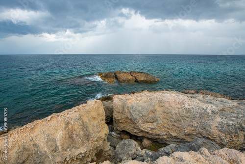 Looking at the sea from the coastal green area. Looking at the sea from the rocks on a cloudy day. Sea view from red cliffs.Cyprus coast.