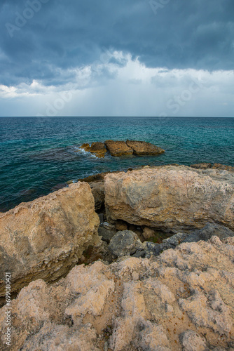 Looking at the sea from the coastal green area. Looking at the sea from the rocks on a cloudy day. Sea view from red cliffs.Cyprus coast.