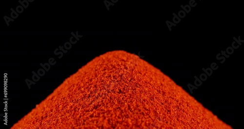 Heap of ground chili pepper or smoked paprika. Sprinkle smoked paprika powder, black background photo