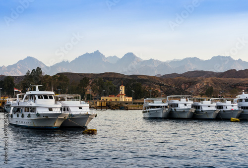 boats standing along the shore in the red sea against the background of mountains and blue sky