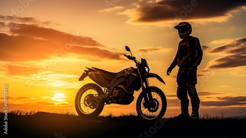 silhouette of a male motorcyclist at sunset and an off-road enduro cross-country motorcycle.