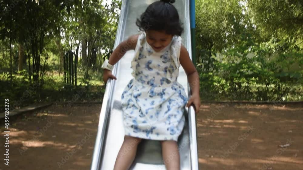 Cute Indian kid smiling and riding down on slide at playground. Slow motion footage. Cute Indian kid smiling and riding down on slide at playground. Slow motion footage.