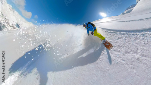 SELFIE, LENS FLARE: Adventurous snowboarder rides fresh snow on untracked slope photo