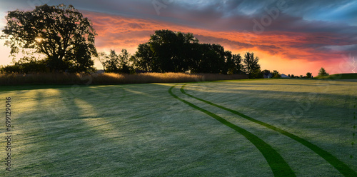 Golf cart tracks on a golf course during a dramatic sunrise