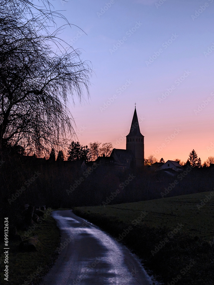 the path to schneppersdelle in ratingen homberg with a view of the church during the blue hour in the colorful evening light 