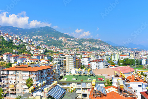City view of multi-storey modern cottages on a mountainside with trees on a summer day. Turkey, Alanya, July 2023.