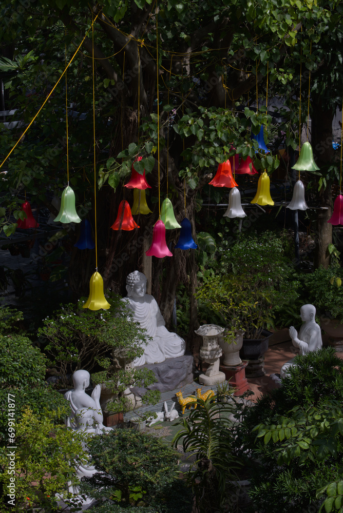 Buddha statue among the trees with Chinese lanterns hanging from the branches