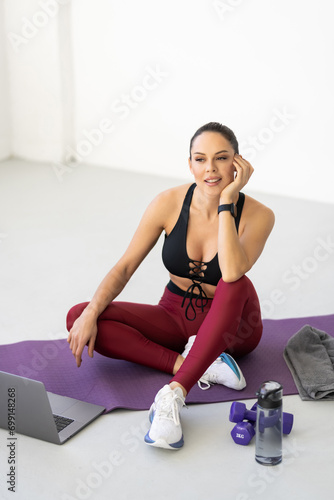 Happy woman in sportswear exercising while watching online fitness class at home