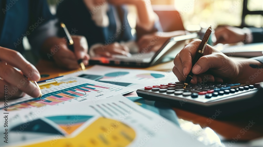 Fototapeta premium business woman holding a pen pointing the graph and partnership to analyze the marketing plan with calculator and laptop computer on wood desk in office