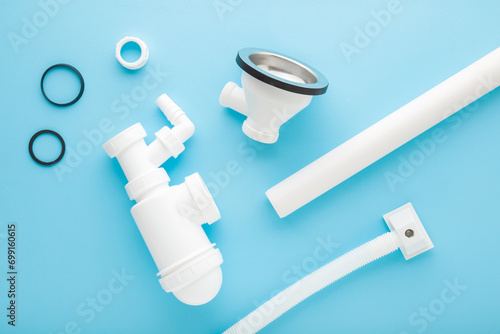 White new plastic parts for sink drain siphon assembling. Light blue table background. Pastel color. Closeup. Top down view. photo