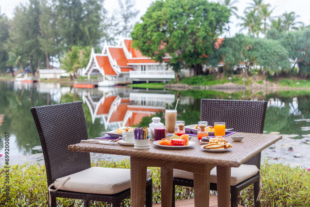 Outdoor breakfast setup at tropical resort with lake view. Travel and leisure.
