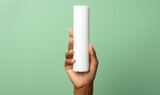 Close-up of Hand Holding White Cylindrical Object on Mint Green Background