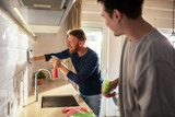 Gay couple cleaning modern kitchen at home