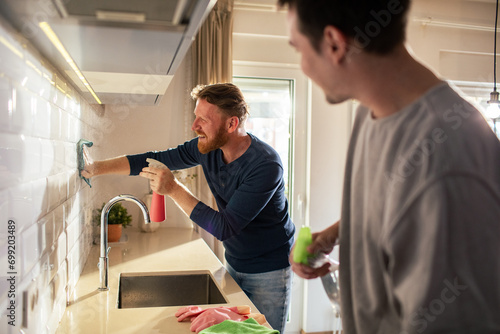 Gay couple cleaning modern kitchen at home photo