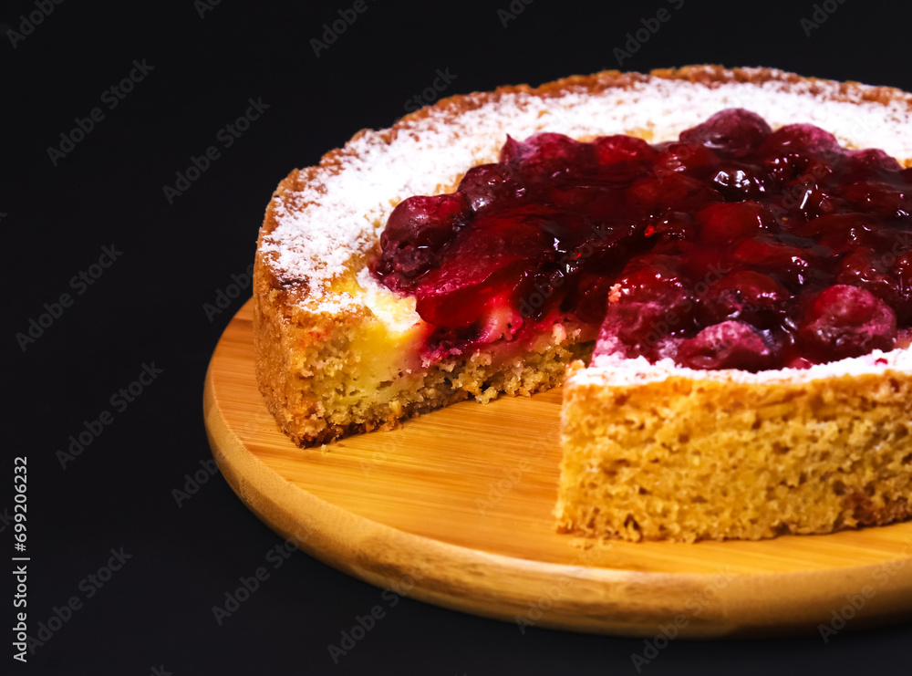 Appetizing cake with raspberry jam and powdered sugar in dark lighting on a wooden board. Close-up Appetizing cake with raspberry jam and powdered sugar in dark lighting on a wooden board. Close-up