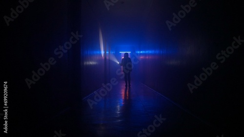Portrait of female in the dark hallway with neon light. Woman with flashlight walking down the hallway in basement exploring it,