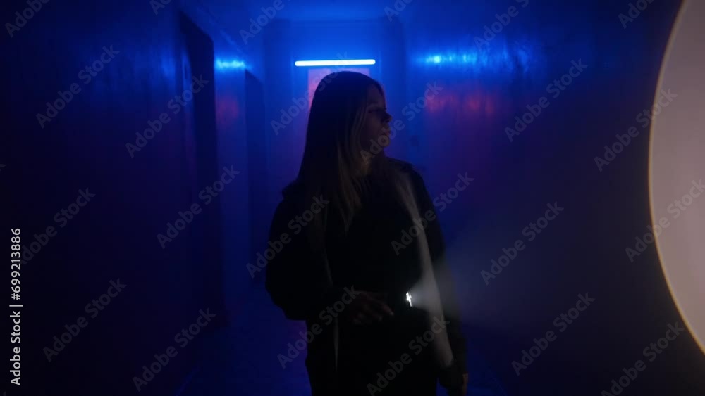 Portrait of female in the hallway blue neon light. Close up shot girl with flashlight facing camera and walking in the corridor. Portrait of female in the hallway blue neon light. Close up shot girl with flashlight facing camera and walking in the corridor.