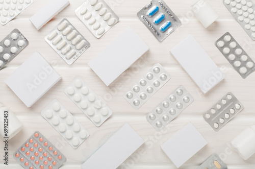 Different pills in blister packaging and boxes and on wooden background, top view