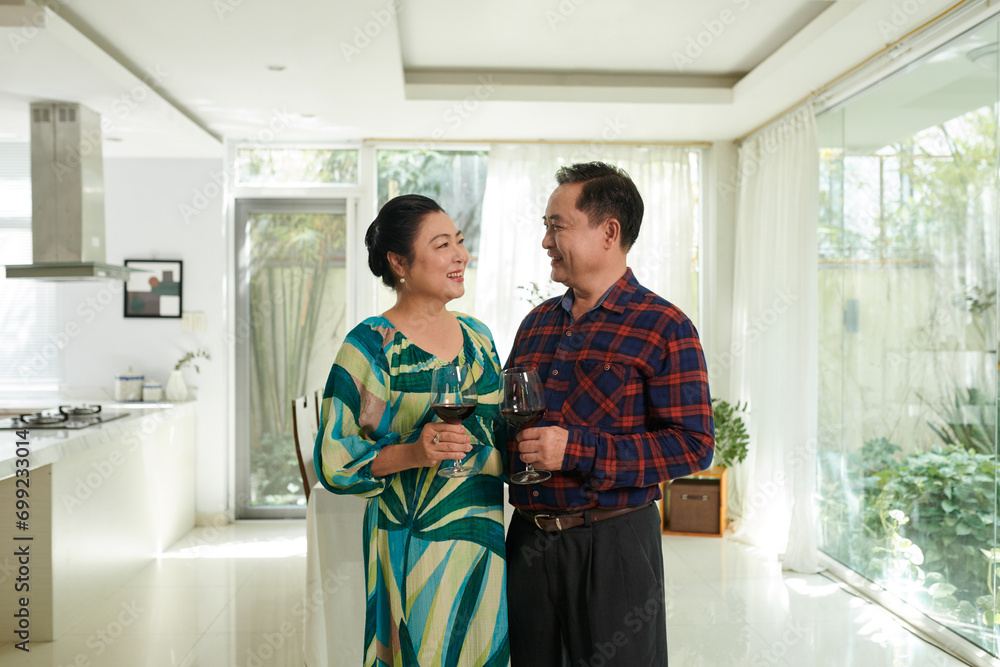 Fototapeta premium Happy Vietnamese senior couple drinking wine when celebrating anniversary at home