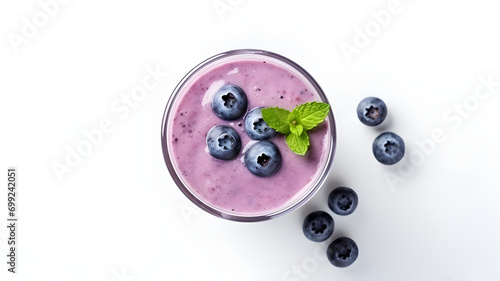 A glass of blueberry smoothie with berries on the table, top view, white background