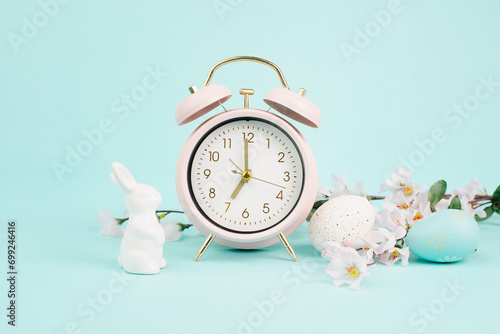 Cute easter bunny or rabbit with an alarm clock, eggs and cherry blossoms, spring holiday, greeting card
