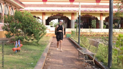 Female tourist with backpack on her shoulders walks through hotel and admires everything around her