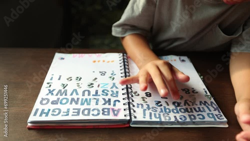 Preschooler learns English letters in his notebook. Education and development of children. 