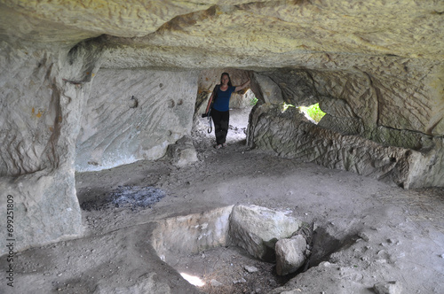 A woman stands in one of the rooms of the cave city of Tepe-Kermen. Bakhchisarai Historical, Cultural and Archaeological Museum-Reserve.
