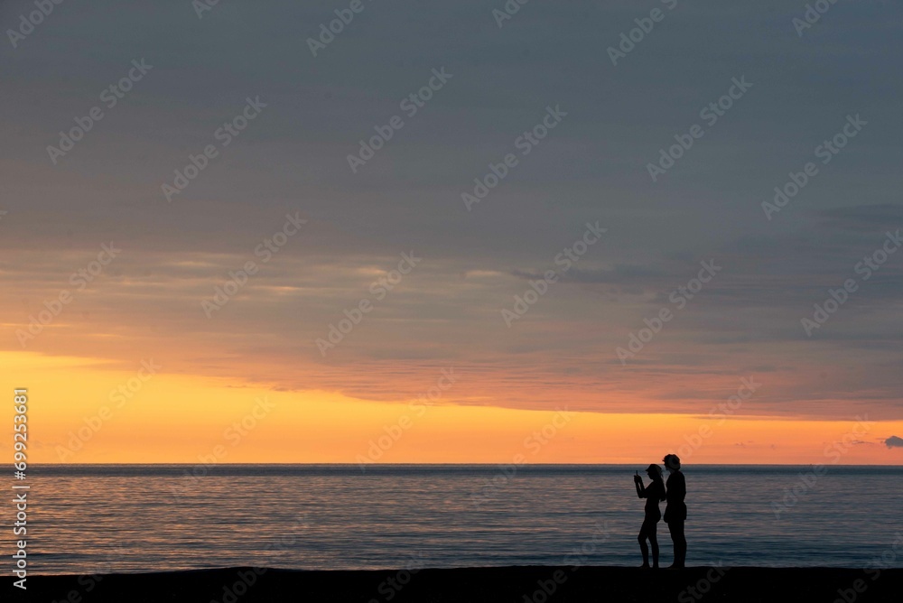 At a beautiful sunset two people on the shore