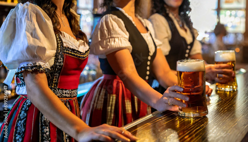 Young women in local dresses celebrating Oktoberfest in Germany by drinking beer in a bar