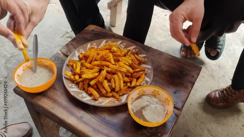 hands picking potato fries served in a ceramic plate and dipping into chatni aka lick'in. photo